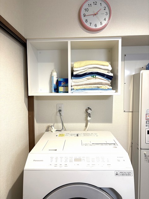 練馬区のH様邸では家具屋による吊戸の設置が行われていました。 74㎝の洗濯機パンを使うので、上部に75㎝幅のオープン棚収納を設けました。 簡単なオープン棚や既製品でも良さそうな場所にわざわざ造作家具を使ったのには理由があります。 もともとこちらのお宅は洗濯機の上にメッシュのオープン棚が1枚あり、そこにフェイスタオルを平置きしてたくさん積んでお使いでした。 というのも、H様は手を洗ったら都度新しいタオルを使う習慣があり（ですのでタオル掛けは必要ありませんでした）、タオルを沢山お使い、かつすぐに手に取れるようオープンな状態が良かったのです。 棚板ではタオルを積んだ時にずれて雑多に見えがちなこと、そしてそれまでは足元に置いて使われていた洗剤も置けるように、ハコ型が良いと思いました。 さらに梁下ということで寸法の制限もあり、わざわざ造作にしたわけです。 前もって伝えておいた形で造ってきてくれ、現場では取付けのみ。 あっという間に取付け完了、ついでと言ってはなんですが、隣のトイレの吊戸棚（こちらは既製品）も取付けしてもらいました。 ささやかな場所のささやかな工夫ですが、生活の中で満足感に大きな差があるのでは…と思っています。